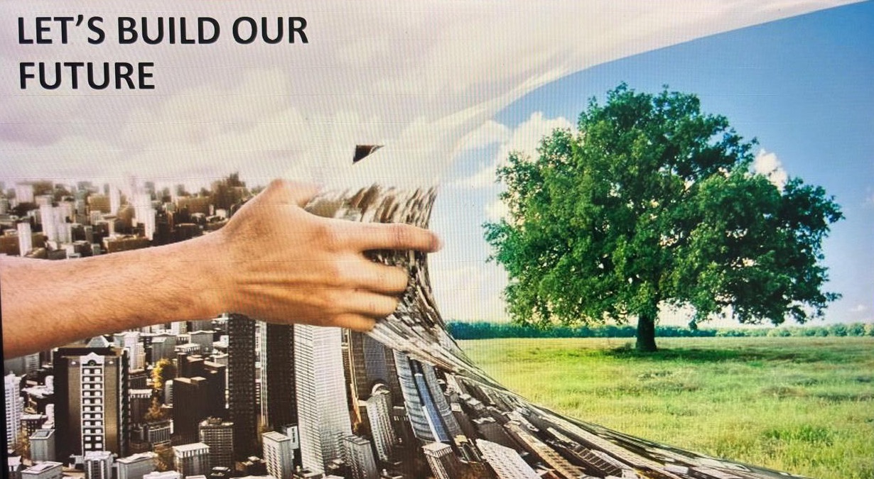 Slide from a sustainability session: 'Let's build our future' — a hand pulls back a cityscape to reveal a green field with a single tree.